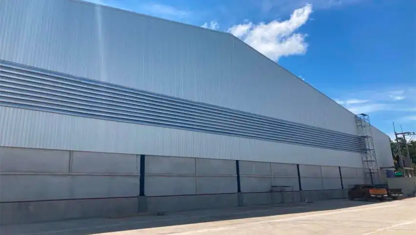 Large branch warehouse exterior with metal siding and concrete base under a blue sky.