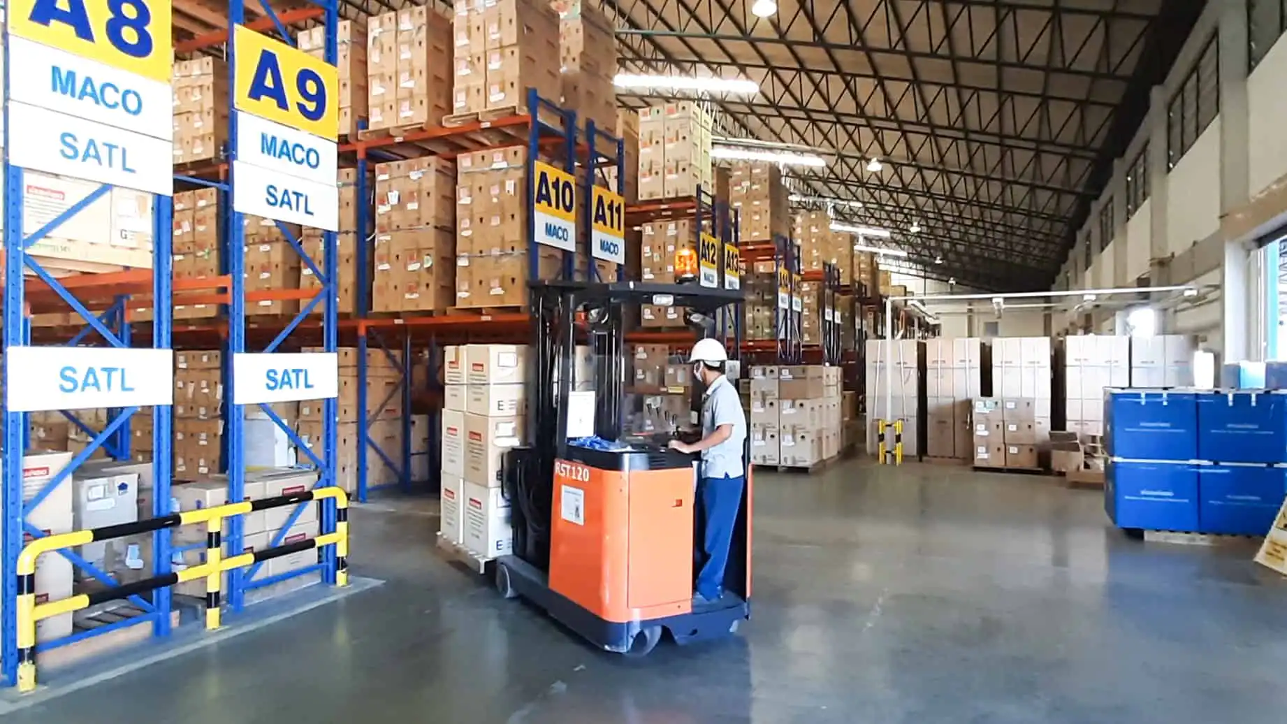 Warehouse interior with worker operating a forklift near labeled storage racks (A8-A13).