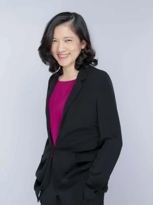 Smiling Asian woman in a black blazer, likely a board member or director.